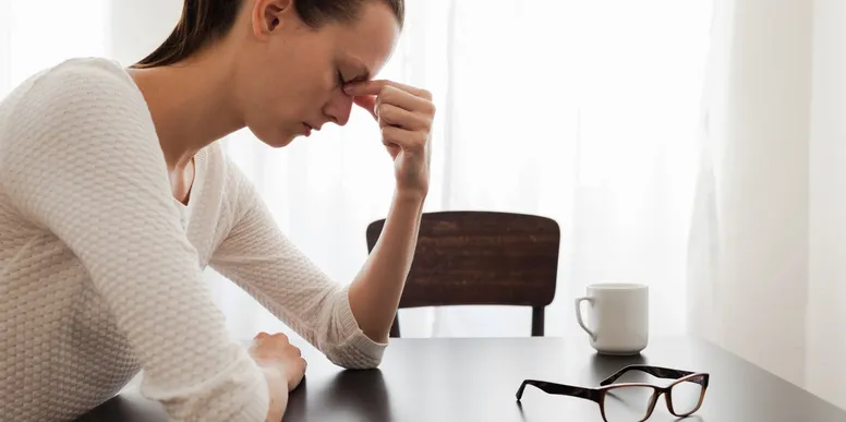A lady holding the bridge of her nose dealing with burnout stress