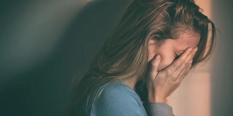 A woman in distress with her face in her hands.